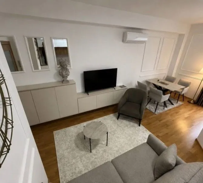 Dnevni boravak sa garniturom, TV-om i trpezarijskim stolom.