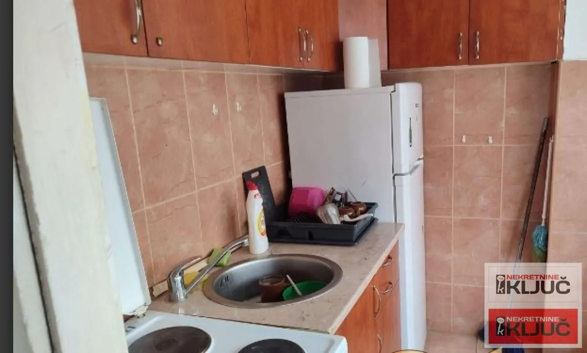 Manja kuhinja sa sudoperom, šporetom i frižiderom.