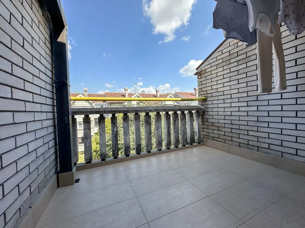Natkriveni balkon sa popločanim podom i pogledom na naselje.