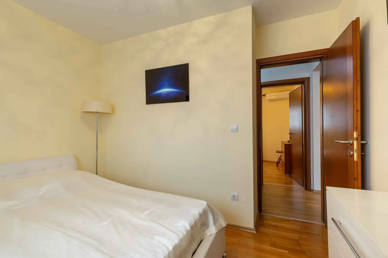 Bedroom with a double bed, floor lamp, and a picture on the wall.