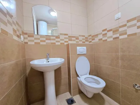 Manje kupatilo sa umivaonikom, ogledalom i wc šoljom obloženo keramičkim pločicama u bež tonovima. - image 4