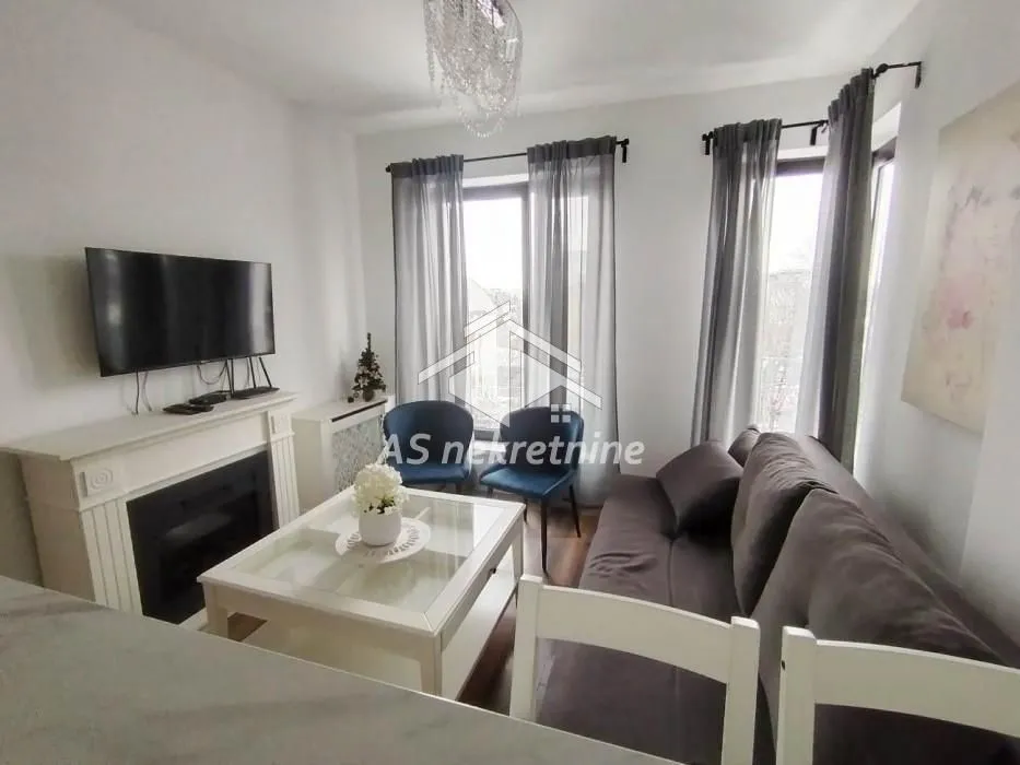 Living room with a sofa, coffee table, fireplace, and wall-mounted TV.