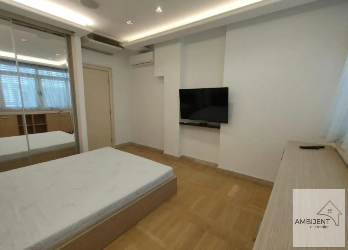 Furnished bedroom with a double bed, fitted wardrobe, and wall-mounted TV.