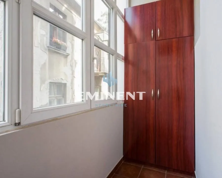 Enclosed balcony with a built-in wooden cabinet and windows.
