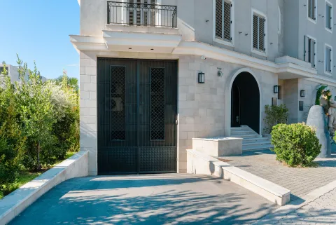 Exterior of a modern residential building with a garage entrance and landscaped yard. - image 3