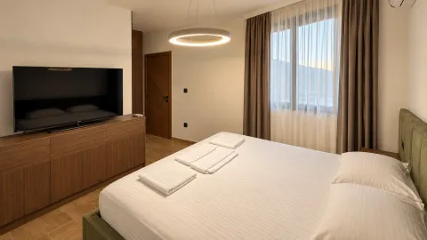 A furnished bedroom with a double bed, TV, and wooden furniture. - image 8
