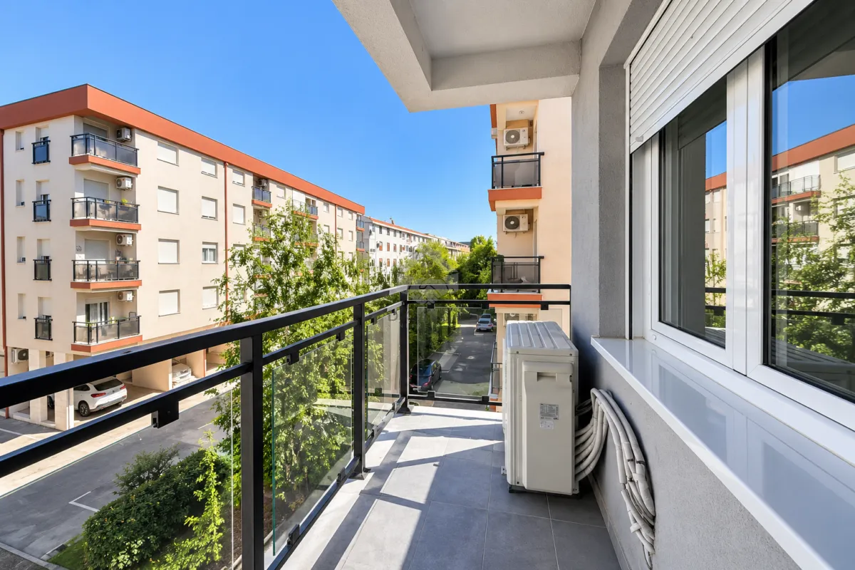 Manji popločani balkon sa pogledom na susjedne zgrade i dvorište.