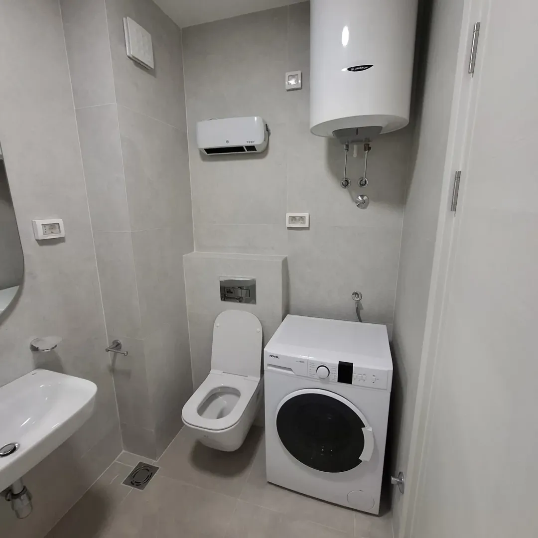 Modern bathroom equipped with sanitary ware, water heater and washing machine.