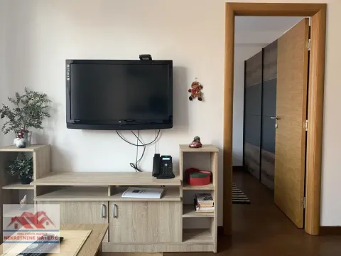 Dnevna soba sa televizorom na zidu i drvenom komodom. - image 6