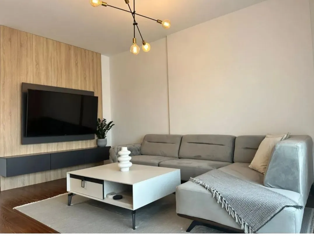 Modern living room with a sectional sofa, coffee table, and TV unit.