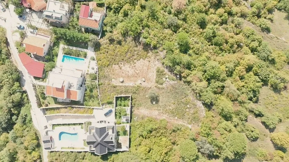 Pogled iz vazduha na imanje sa kućama, bazenom i okolnim zelenilom.