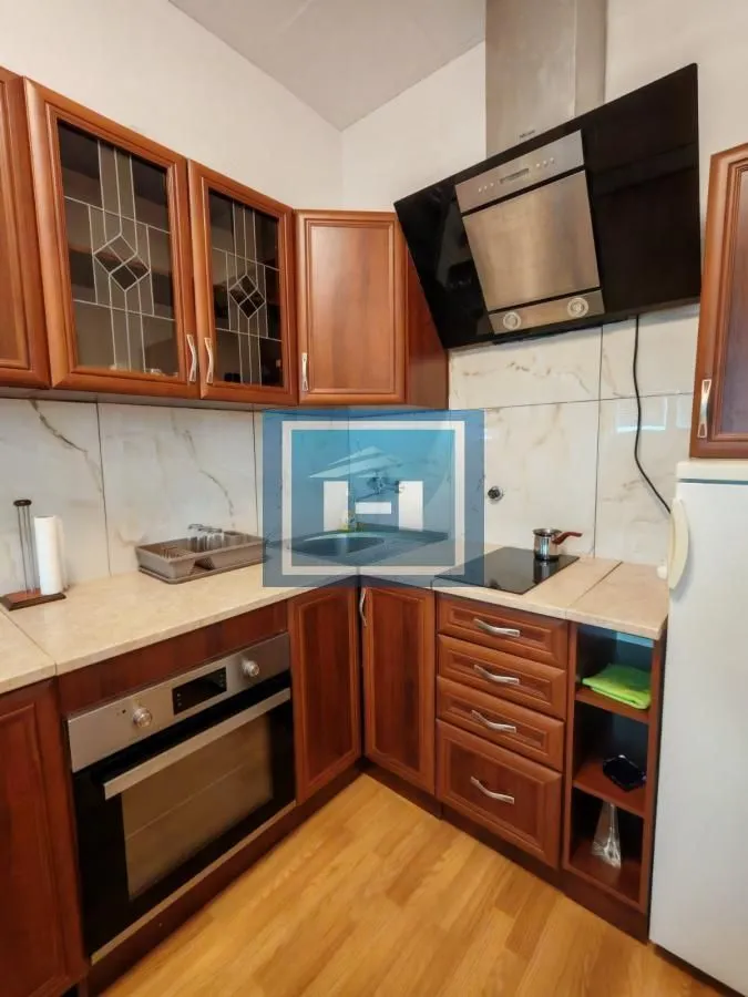 Kitchen with wooden cabinetry, built-in oven, and extractor hood.