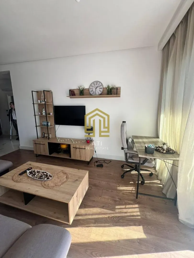Dnevni boravak sa garniturom, TV komodom i radnim stolom.