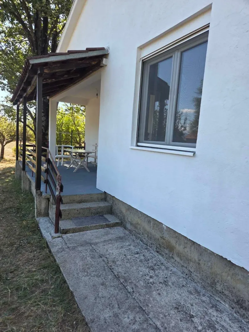 Pogled na ulazni dio kuće sa natkrivenom terasom i stepeništem.