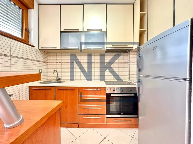 Kitchen with wooden cabinets, built-in appliances, and a refrigerator.