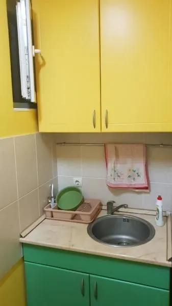 Small kitchen with a sink, countertop, and yellow and green cabinets.