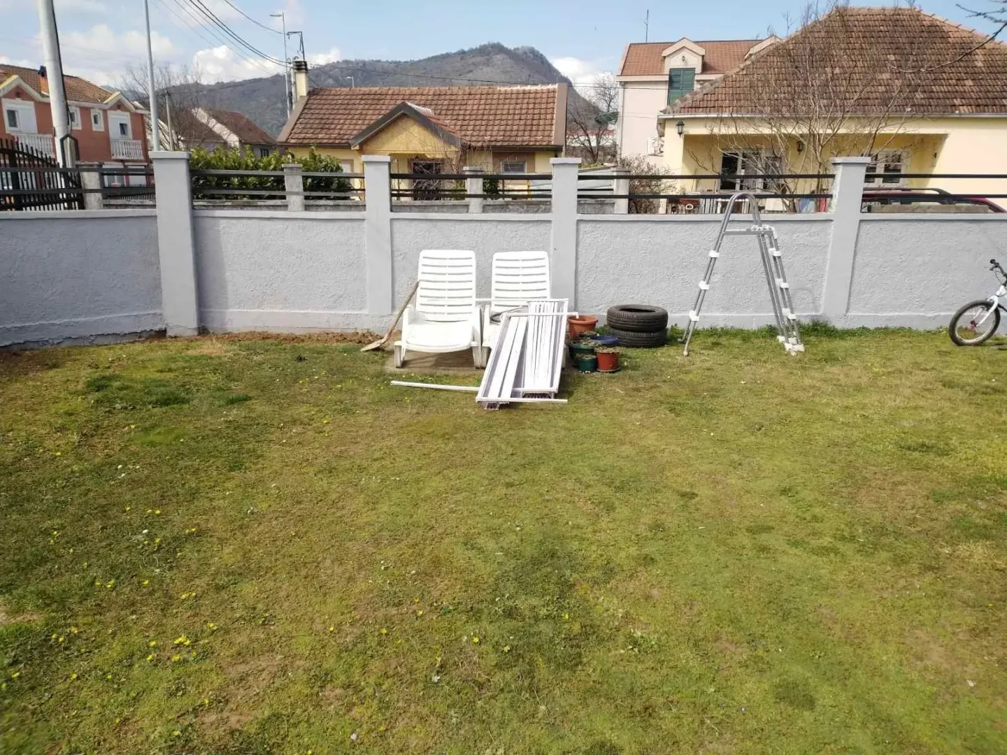 A house yard with a lawn and a concrete fence.
