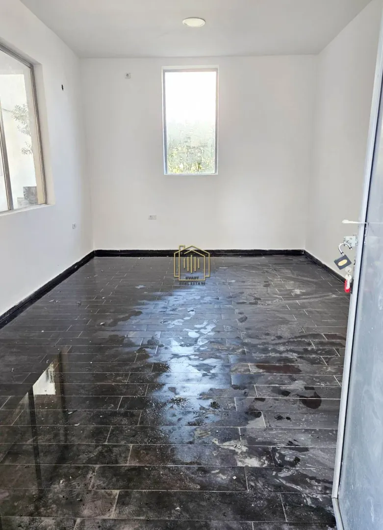 Empty room with white walls and dark floor tiles.