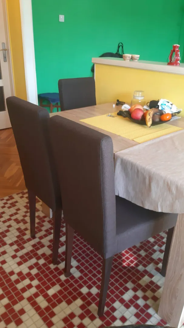 Trpezarija sa stolom i stolicama u stanu.