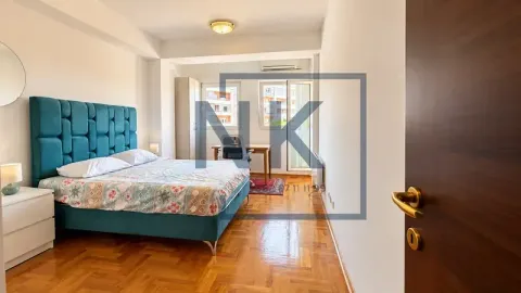Spacious bedroom with a large double bed, a desk, and parquet flooring. - image 7