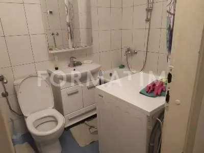 Smaller bathroom with a washbasin, toilet, bathtub, and washing machine.