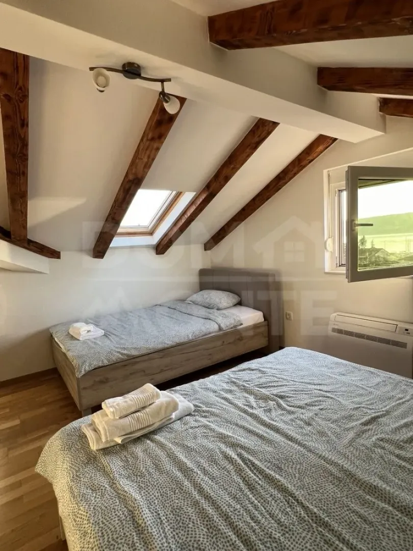 Attic bedroom with two beds and wooden beams.