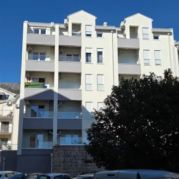 Exterior of a modern residential building with balconies and parked cars in front. - image 11