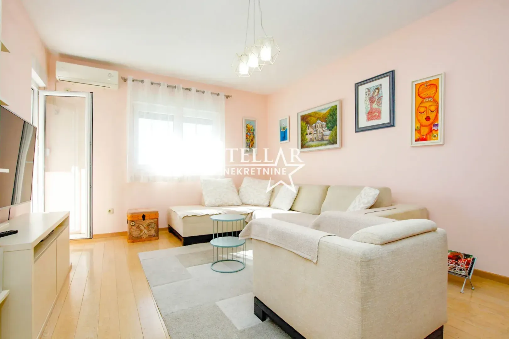 Living room with a sofa, armchair and paintings on the wall.