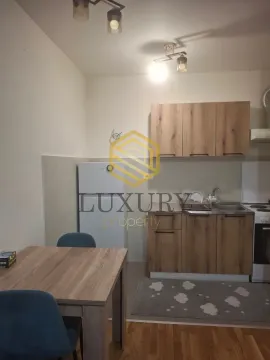 Smaller kitchen with wooden cabinets and a dining table. - image 4