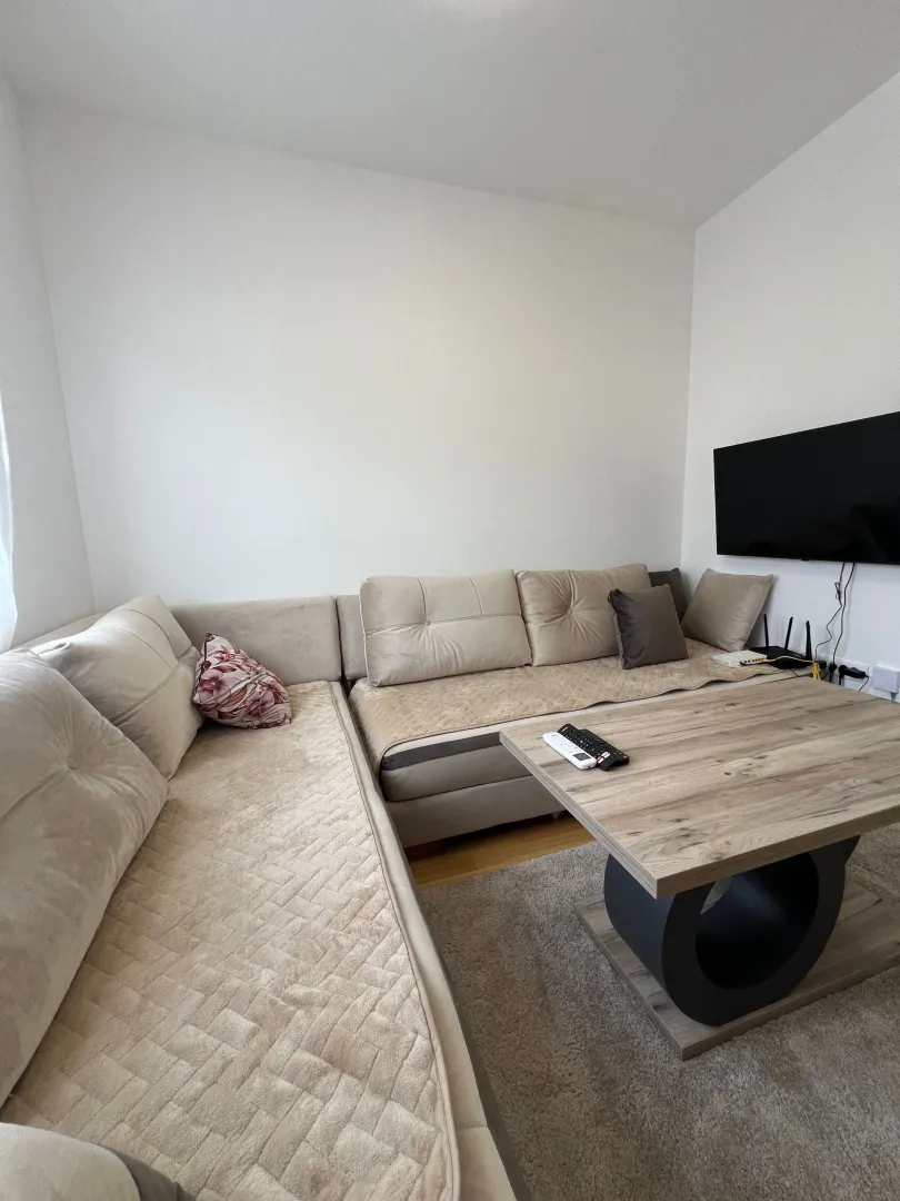 Living room with a sectional sofa, coffee table, and wall-mounted TV.