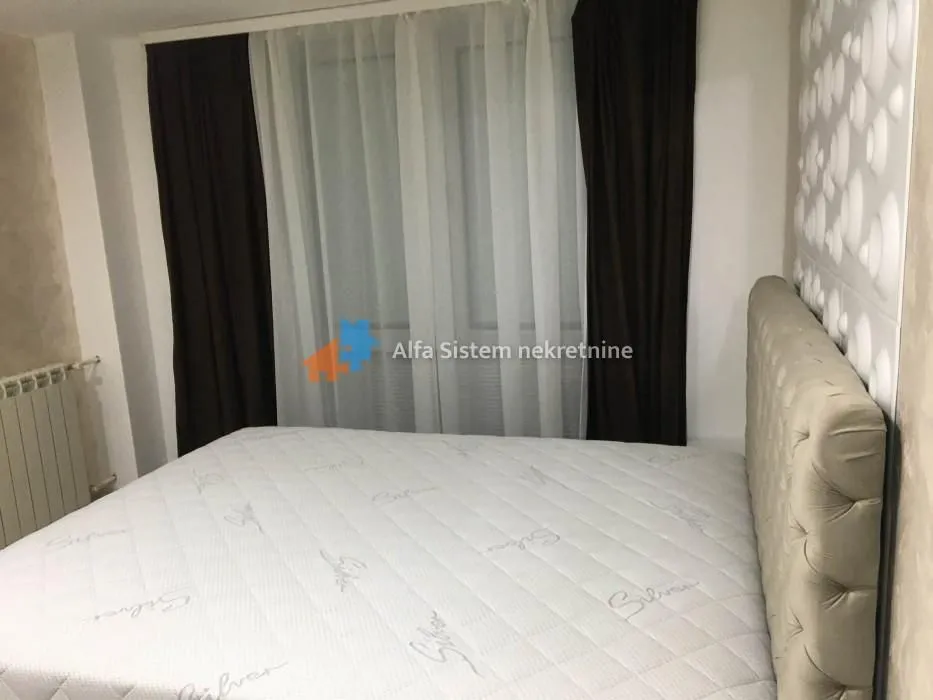 A bedroom with a double bed and a window with curtains.