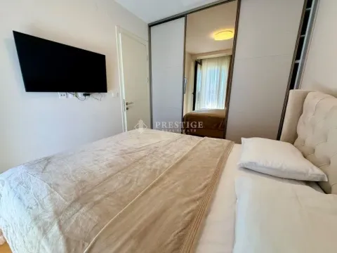 Moderna spavaća soba sa bračnim krevetom, plakarom i televizorom na zidu. - image 10