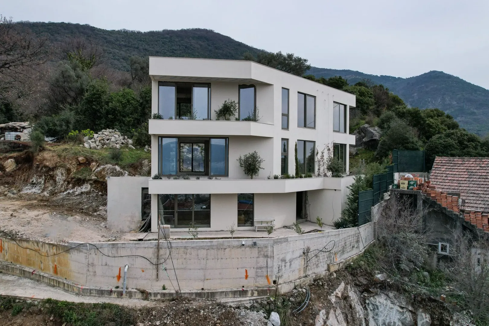 Pogled na modernu višespratnu zgradu okruženu brdskim pejzažom.