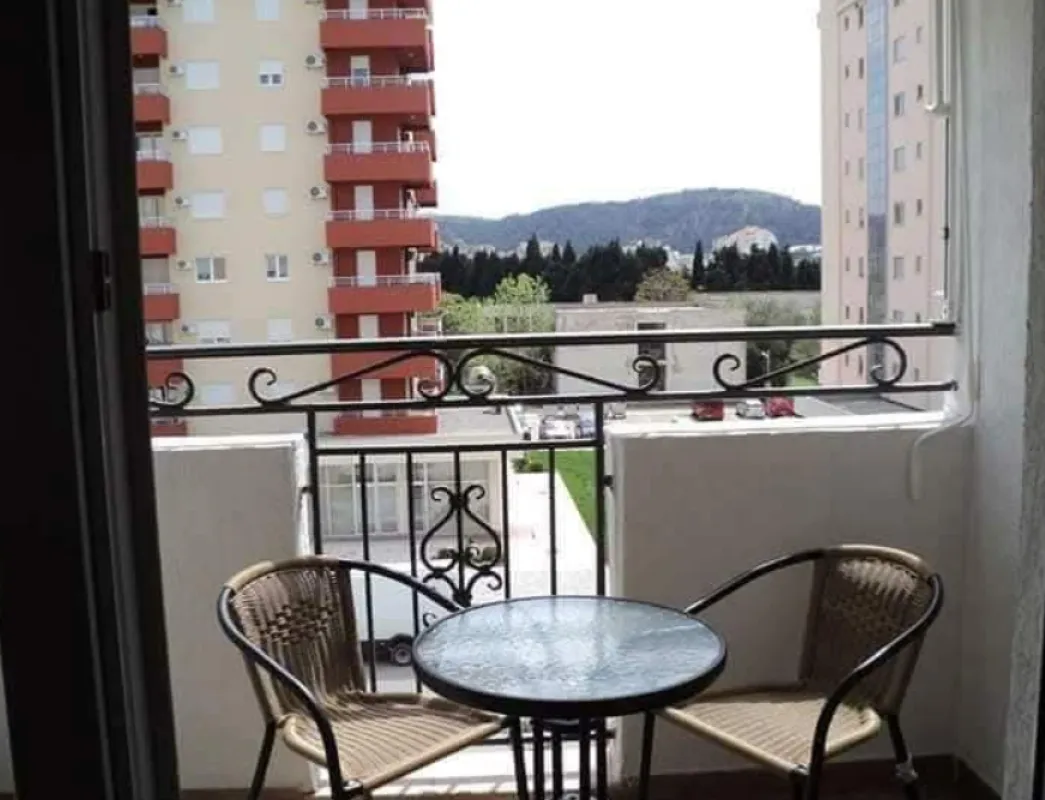 Manji namješteni balkon sa stolom i dvije stolice i pogledom na okolne zgrade.