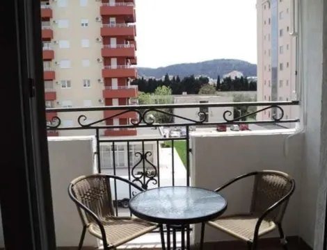 Manji namješteni balkon sa stolom i dvije stolice i pogledom na okolne zgrade. - image 4