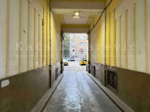 Natkriveni prolaz zgrade sa pogledom na dvorište i parkirana vozila. - image 15