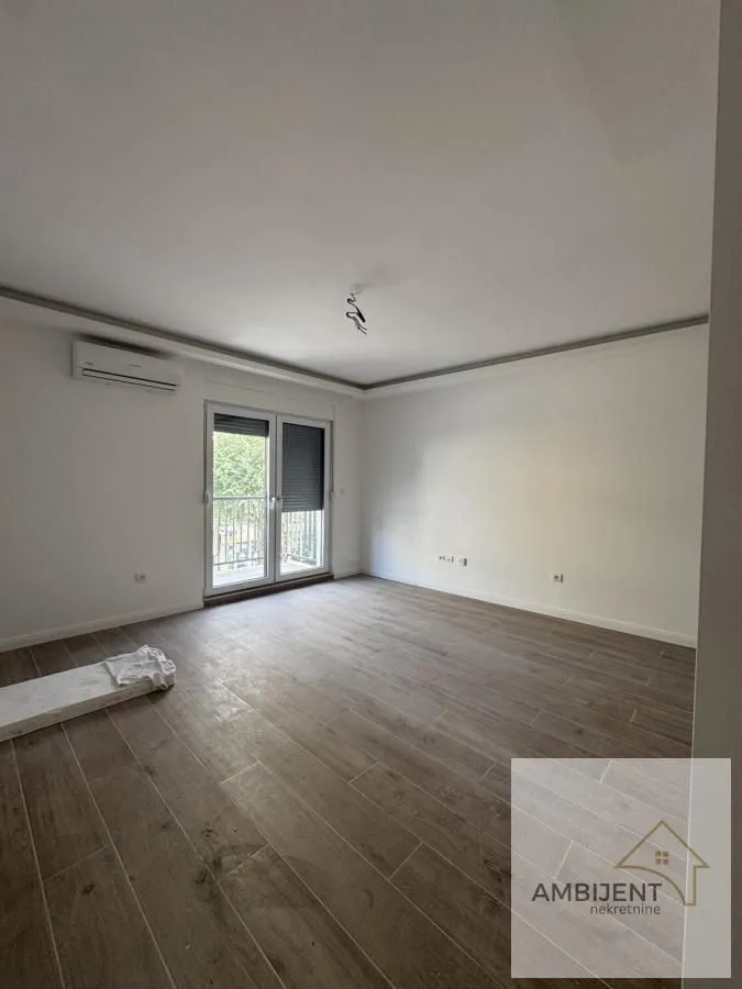 Prazna soba sa laminatom i izlazom na terasu.