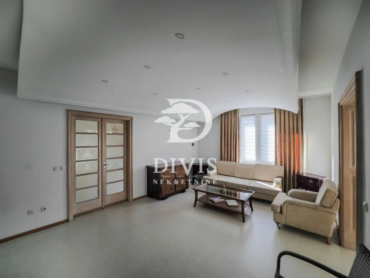 Spacious living room with seating furniture and a drop ceiling.