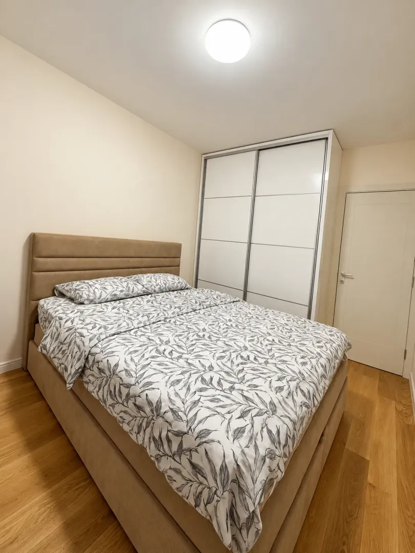 Furnished bedroom with a double bed, wardrobe, and wooden flooring.