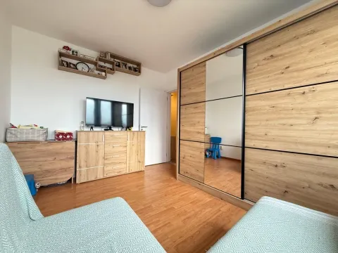 Spavaća soba sa velikim drvenim garderoberom sa ogledalom i komodom sa televizorom. - image 11