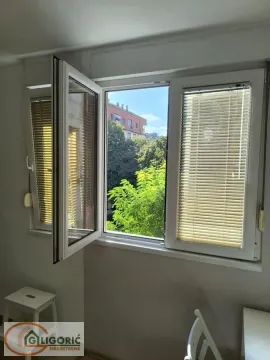 A view through an open window with blinds towards surrounding buildings and greenery. - image 6