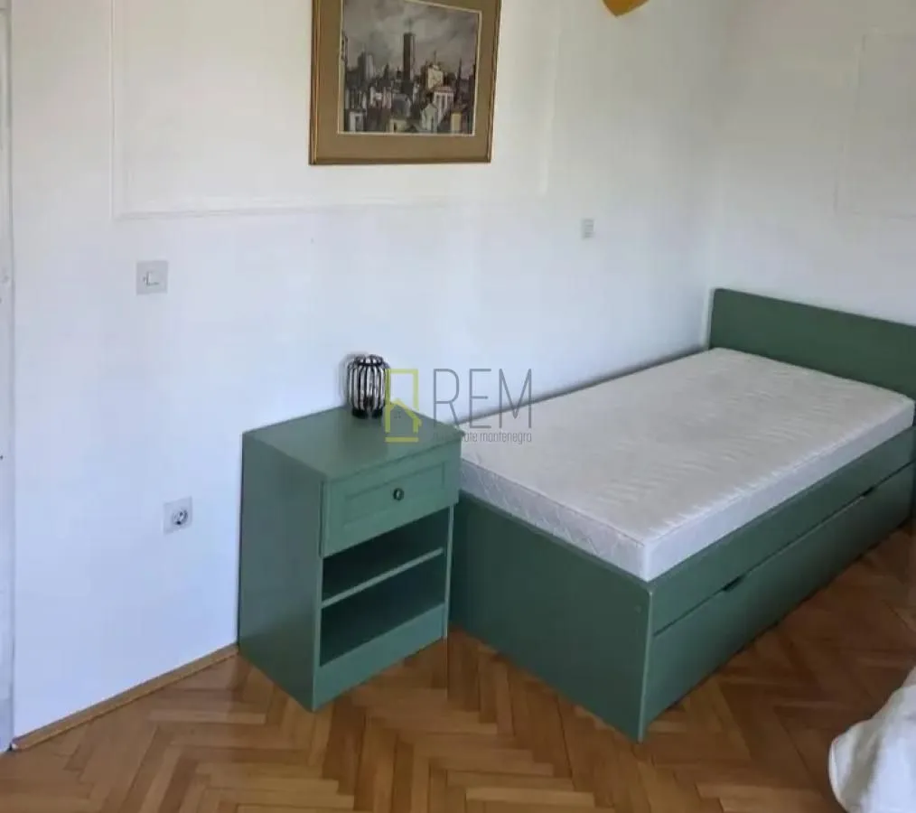 Manja spavaća soba sa krevetom i noćnim stočićem.