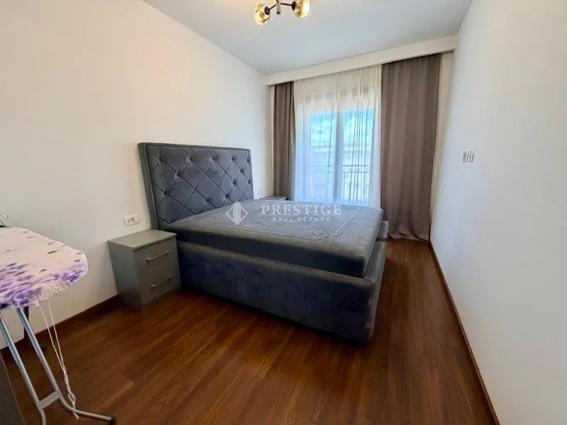Furnished bedroom with a double bed, nightstand, and a window with curtains.