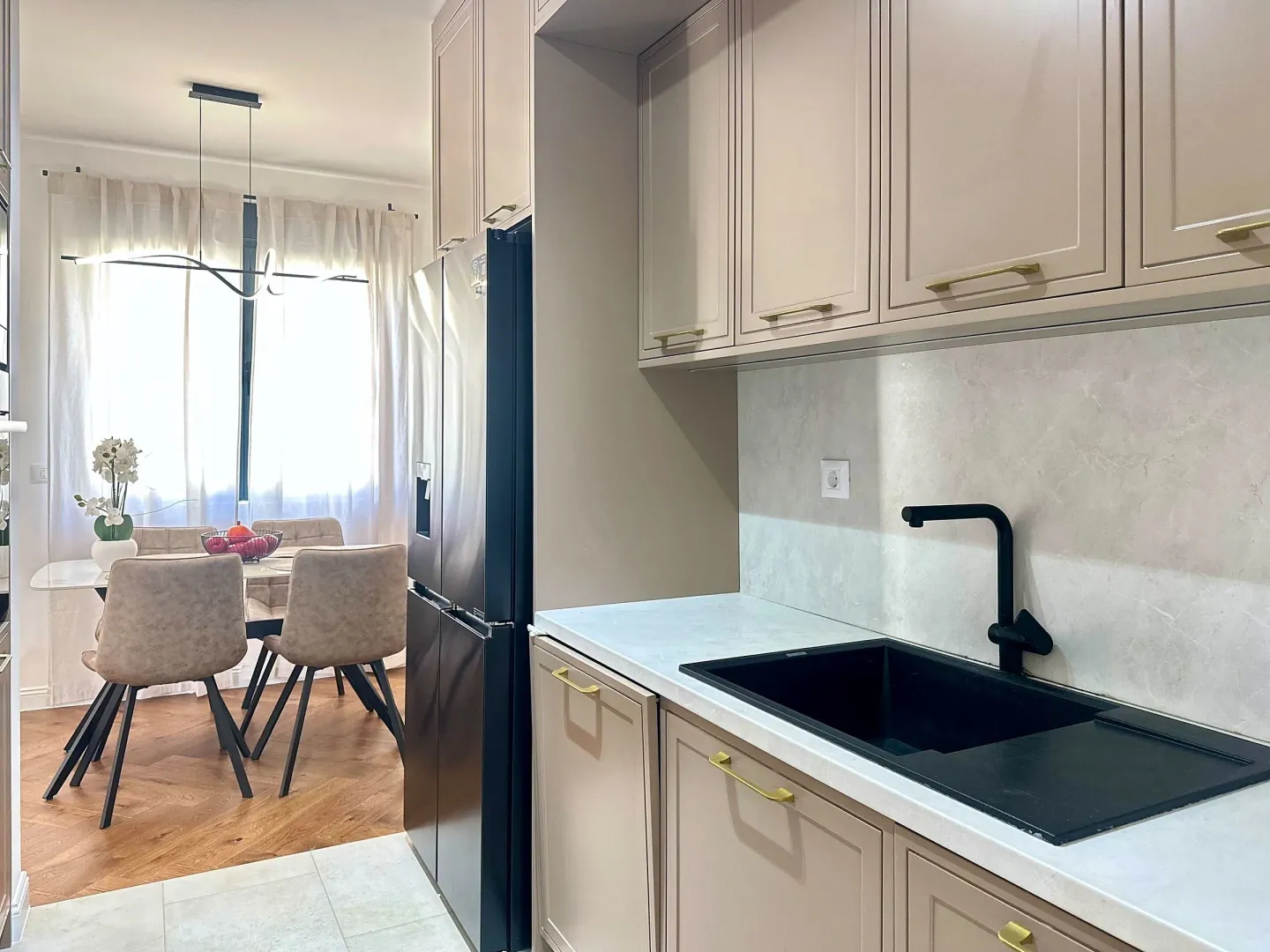 Modern kitchen with beige cabinets and a view of the dining area.