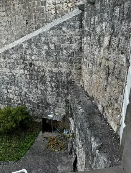 View of the exterior yard area with stone walls and a sink.