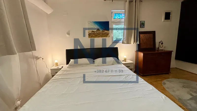 Furnished bedroom with a double bed, bedside tables, and a wooden chest of drawers.