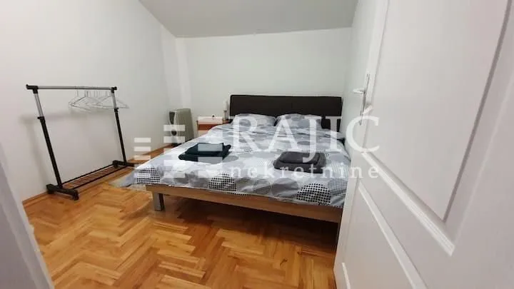 Furnished bedroom with a double bed and parquet flooring.