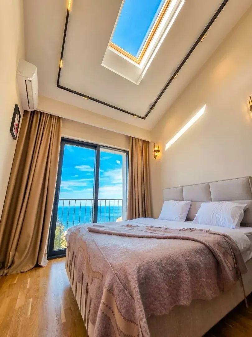 Bedroom with a double bed, skylight, and balcony door offering a sea view.