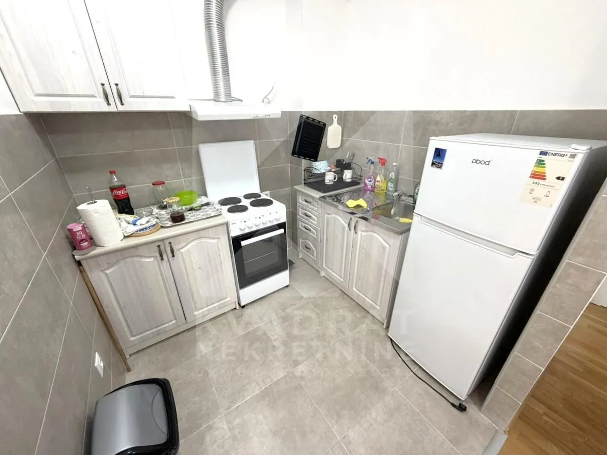 Small equipped kitchen with white cabinets, stove, and refrigerator.