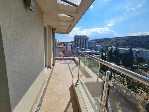 Spacious tiled balcony with a glass railing and a city view. - image 6